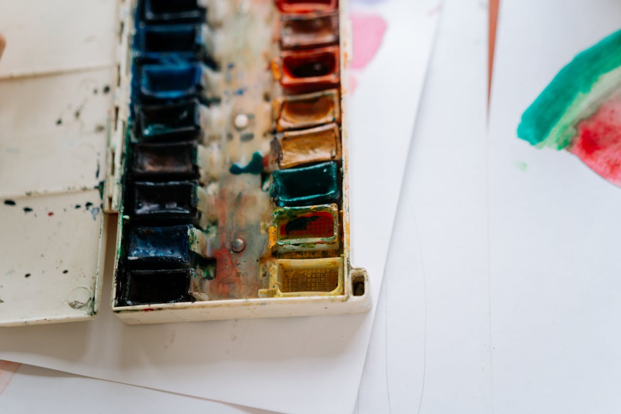 Detailed close-up of a colorful watercolor paint palette with brush strokes on paper.